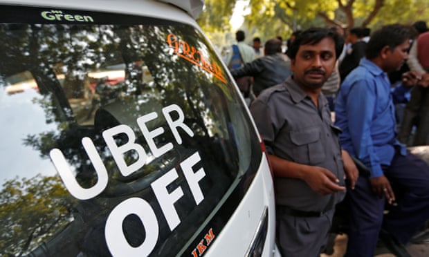 Uber and Ola drivers stand next to their parked vehicles during a protest in New Delhi in 2017