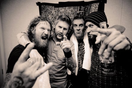 Mastodon with their arms around one another pointing at the camera