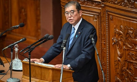 Japan’s prime minister, Shigeru Ishiba, speaks in parliament surrounded by mics.