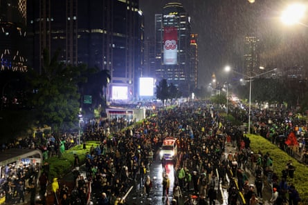 An ambulance makes its way among protesters as they run away after riot police fire teargas during a protest outside Jakarta police headquarters in Jakarta, Indonesia, 29 August, 2025.