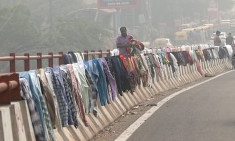 A man hangs clothes to dry in on barriers as Delhi is engulfed by heavy smog.