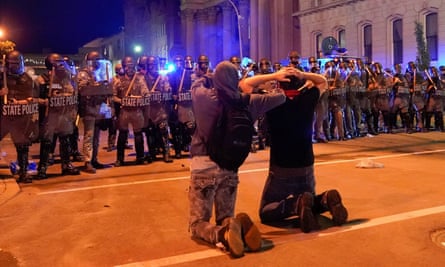 Two men kneel in front of a line of state troopers during a protest in Louisville, Kentucky, on 1 June.