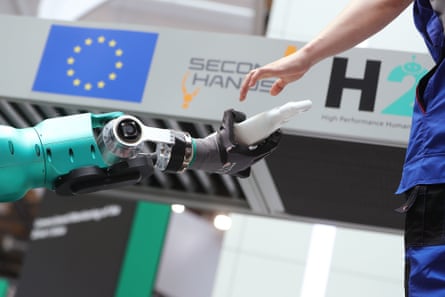 Um robô humanóide ajuda seu companheiro humano em uma demonstração em uma feira de tecnologia na Alemanha.