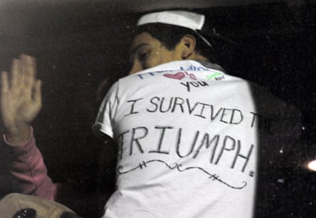 person wearing white shirt that has 'I survived the Triumph' written in black marker