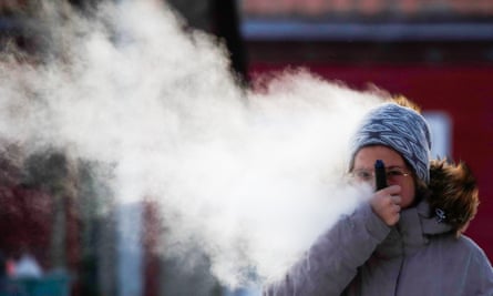 A woman vaping in a street.