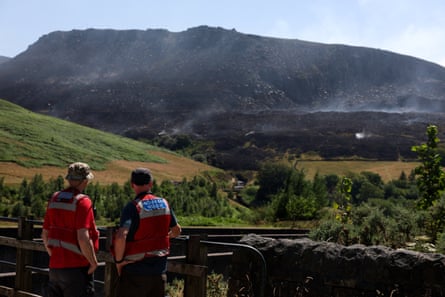 Emergency services members look at smoke rising from a moorland blaze, near the Dovestone Reservoir, in Manchester.