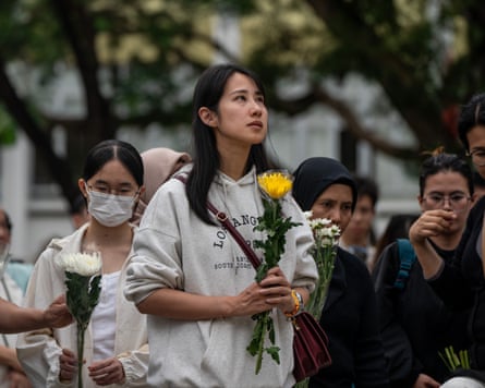 A female mourner holding a yellow flower