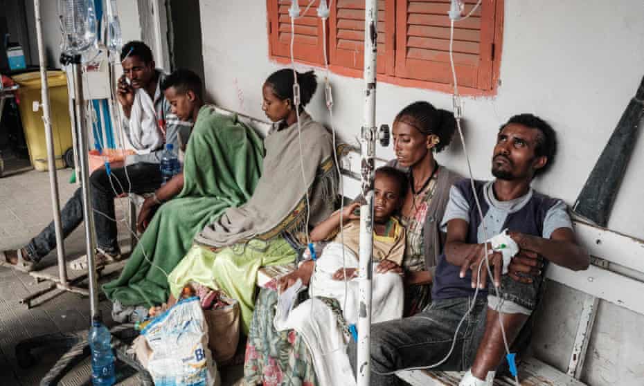 People who were injured in their town Togoga in a deadly airstrike on a market, wait on a bench for medical treatment.