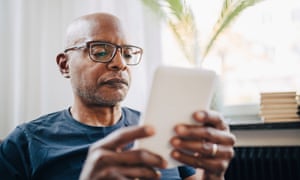 Retired senior man reading e-book in room at home