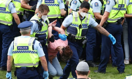 A woman is arrested and carried away as protesters refuse to leave parliament grounds in Wellington.