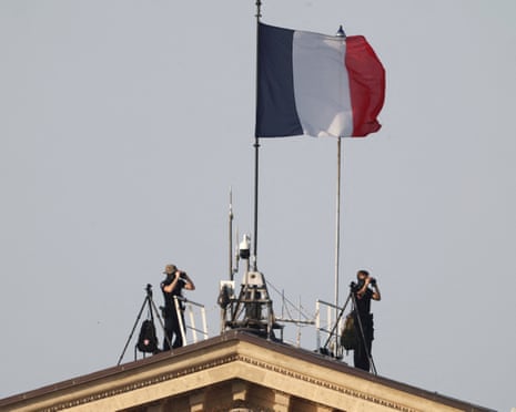 A French flag flies as members of French security services observe the Place de la Concorde from the top of the National Assembly prior to the start of the annual Bastille Day military parade in Paris, France.