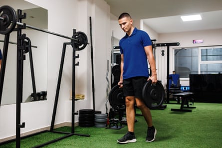 A man in a gym performs a farmer’s carry.