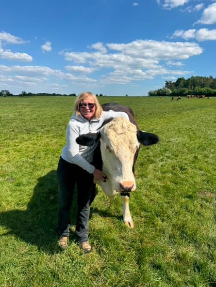 A woman stands in a field hugging a cow