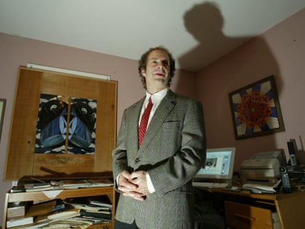 man in a suit in an office with a big shadow on the wall behind him