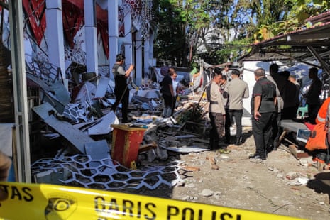 Police officers examine a destroyed building in Manado, North Sulawesi