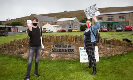 Two protesters waiting for Boris Johnson during his visit to Stromness, Orkney.