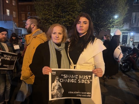 Two women hold a poster which reads “Shame must change sides”.