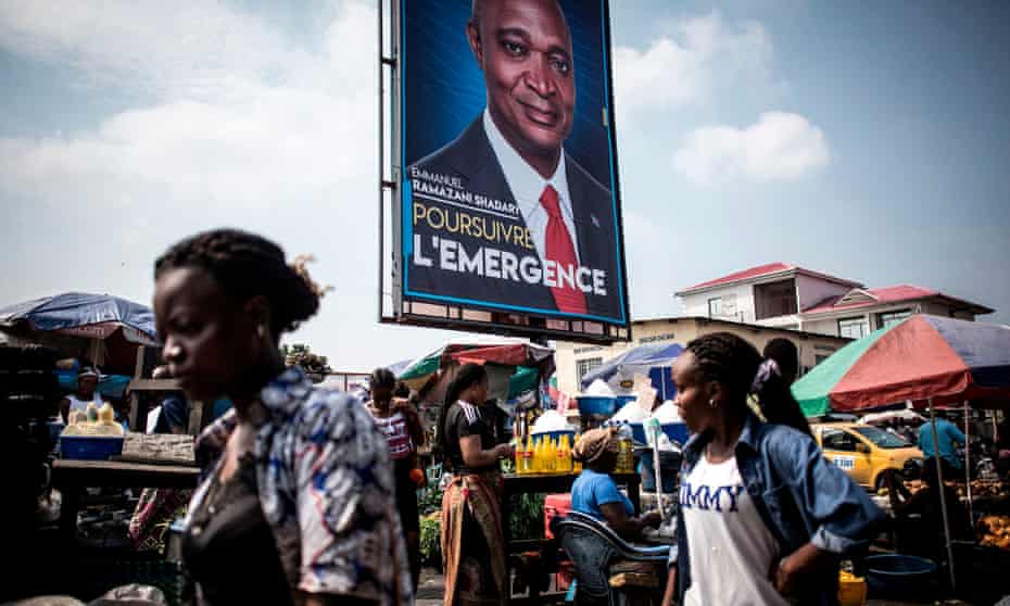 Women walk past a campaign poster of Joseph Kabila’s chosen successor as president of DRC Emmanual Ramazani Shadary in Kinshasa on 18 December 2018