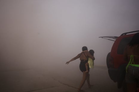 A woman runs with a kid in the dusty air