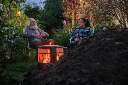 Pearce Quigley and Lauren Patel sitting in garden chairs around a fire pit