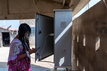 A Wayúu woman charges her phone using power delivered by solar panels