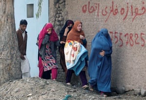 Afghan women leave the site of a blast and gun fire in Jalalabad, Afghanistan