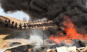 Tires burn as soldiers and law enforcement officers stand in formation to force Dakota Access pipeline protesters off private land.