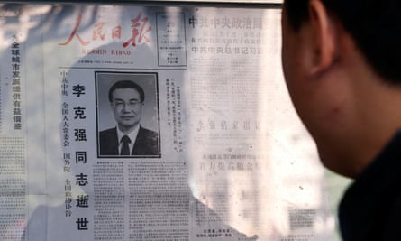 A man reads a newspaper with an obituary of Li Keqiang on a bulletin board in Beijing.