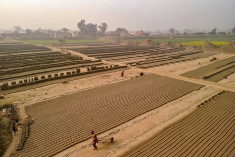Workers, seen from afar, in a brick kiln field