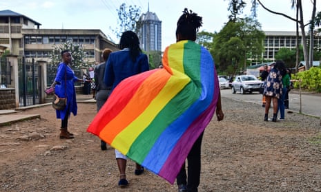 A group of people in Kenya, one of whom has the gay pride flag draped over their shoulders.