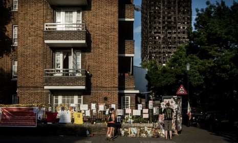Passersby read cards and flowers left near the shell of Grenfell Tower, west London.