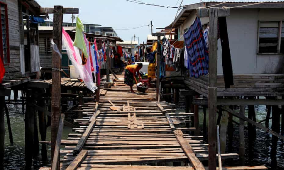 A woman washes clothes amid stilt houses at a village in Port Moresby, Papua New Guinea