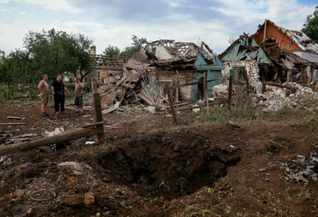 Local residents stand next to the destroyed buildings following a rocket attack in the town of Kramatorsk in the Donetsk region on 13 August, 2022.