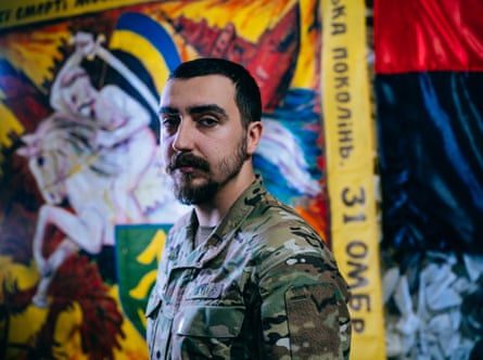 Ruslan poses in front of a banner displaying an image of a Cossack warrior on horseback