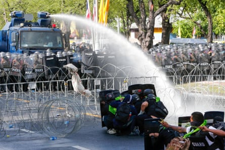 Riot police spray water cannon at protesters outside Government House in Bangkok.