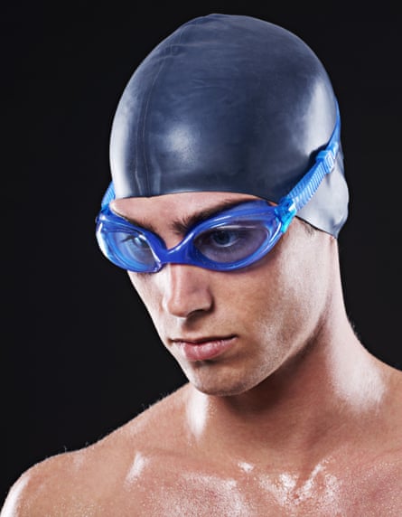 Studio portrait of a young male swimmer with goggles and cap