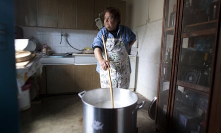 Stirring stuff: a Cypriot woman stirs whey, next to her drinks cabinet in the kitchen.
