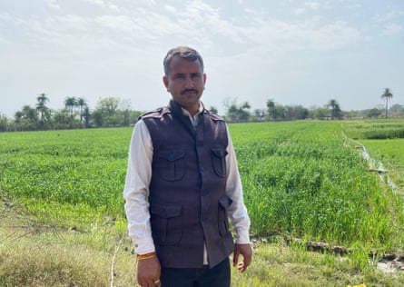 Surajpura village council head Ramlal Jat poses for a picture in front of the revived farms of Surajpura
