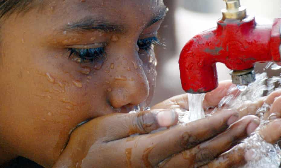 A child drinks water from a tap in a slum