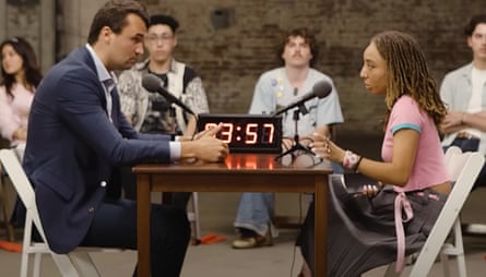 A young woman debates with a man in a suit while other students watch surrounding them
