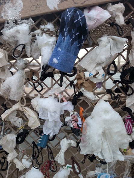 A bridge fence covered with locks, rubber bands, hair ties, tampons, and a sock