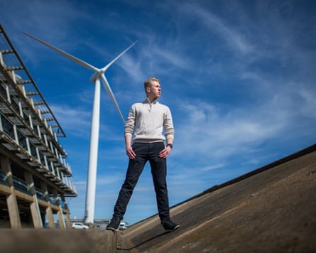 Jake Snell, a young man stands in front of a wind turbine.