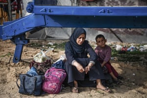 A Palestinian woman sits with a young boy on one side and bags on the other