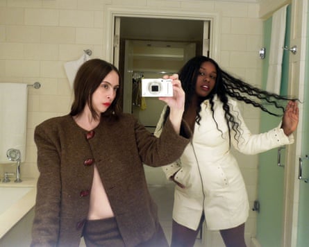 Two women take a selfie in a bathroom mirror