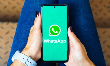 A person holding a smartphone showing the WhatsApp logo