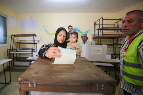 A woman holding a young child casts her ballot in the elections.