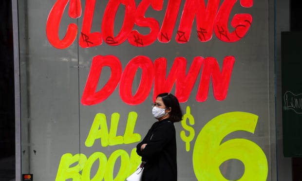 A woman walks past a closing down sign on an empty shop in Melbourne’s central business district