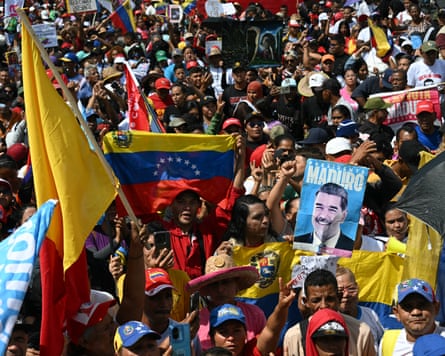 Crowds holding up flags and signs in support of Maduro