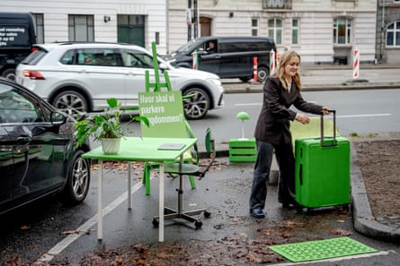 Woman moves bright green furniture around in a parking space in the city centre