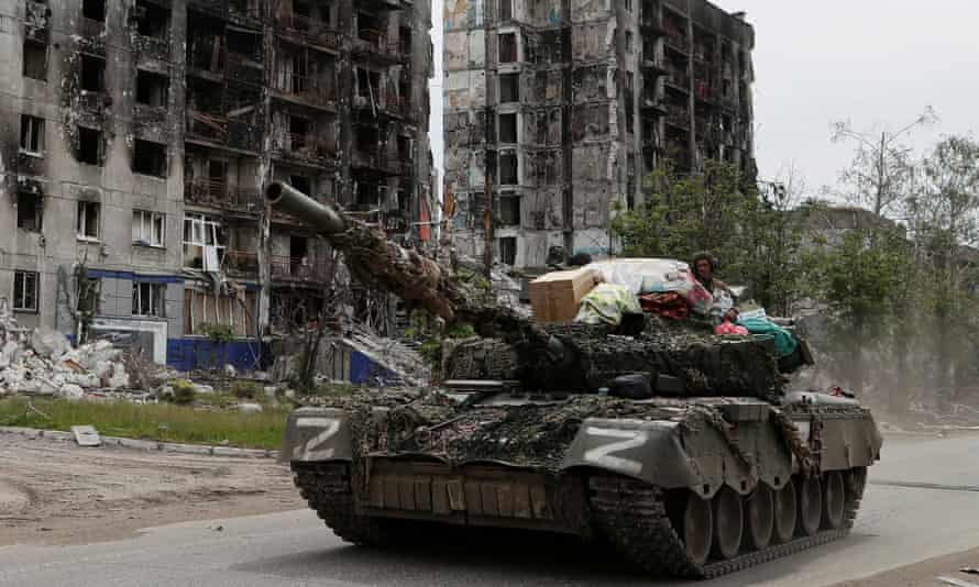 Pro-Russia forces drive past a destroyed residential building in Popasna, Luhansk